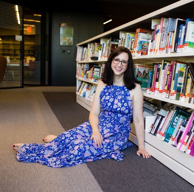 woman sitting on floor in front of bookshelf